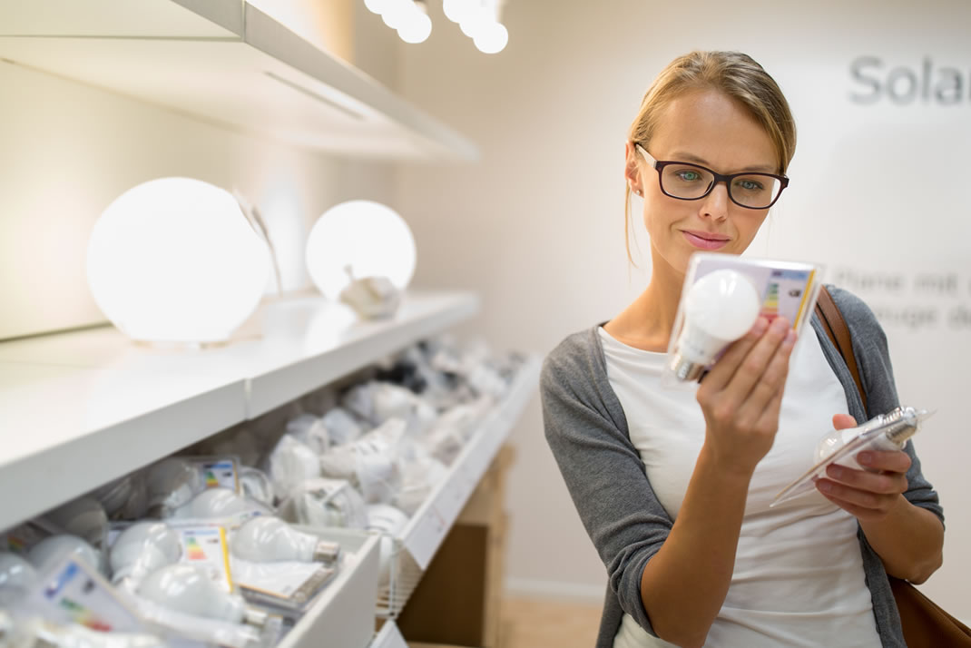 Young woman considering LED light bulbs in a store